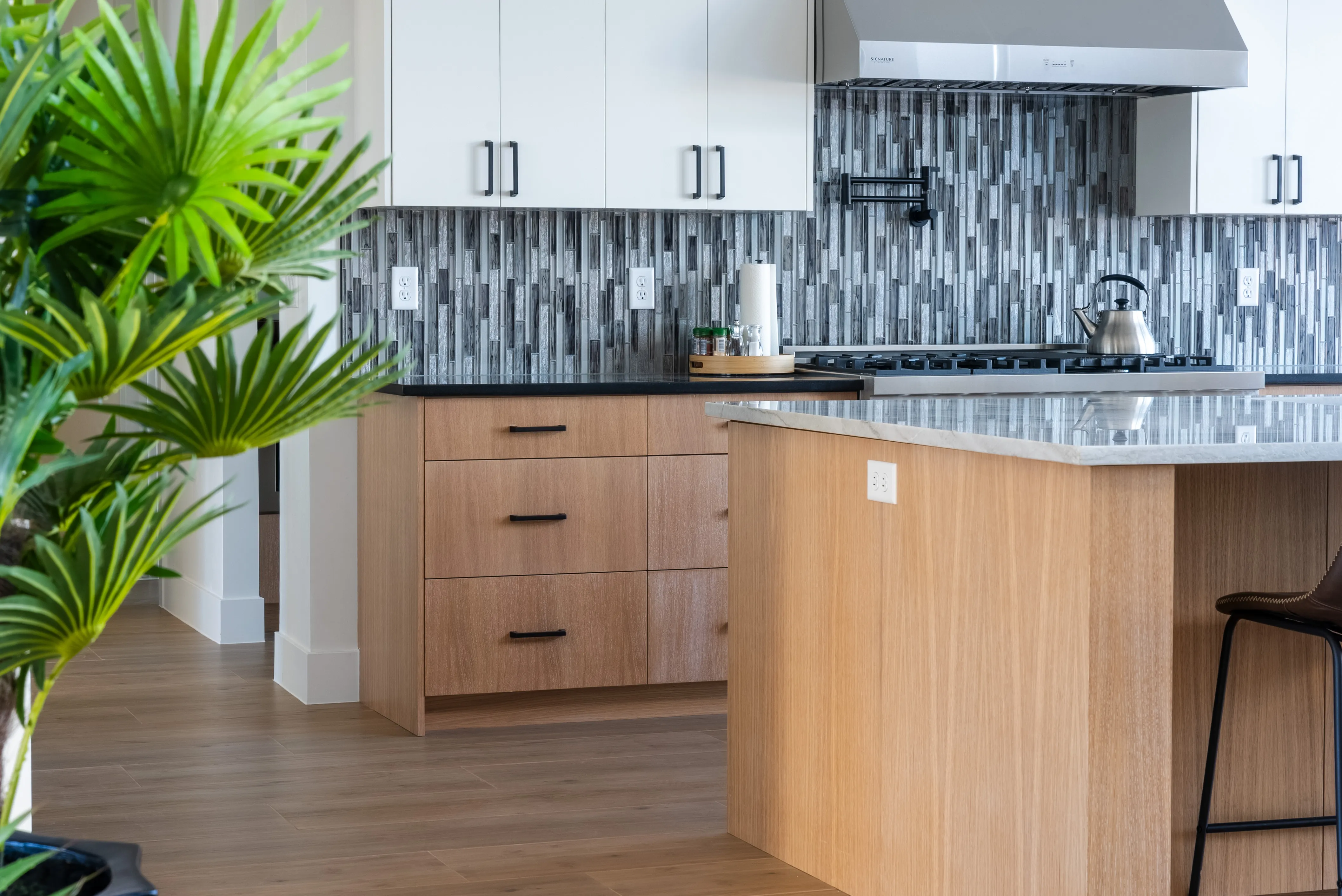 White slab uppers over oak base cabinets with a dark glass-mosaic backsplash, from our Pecan Valley build