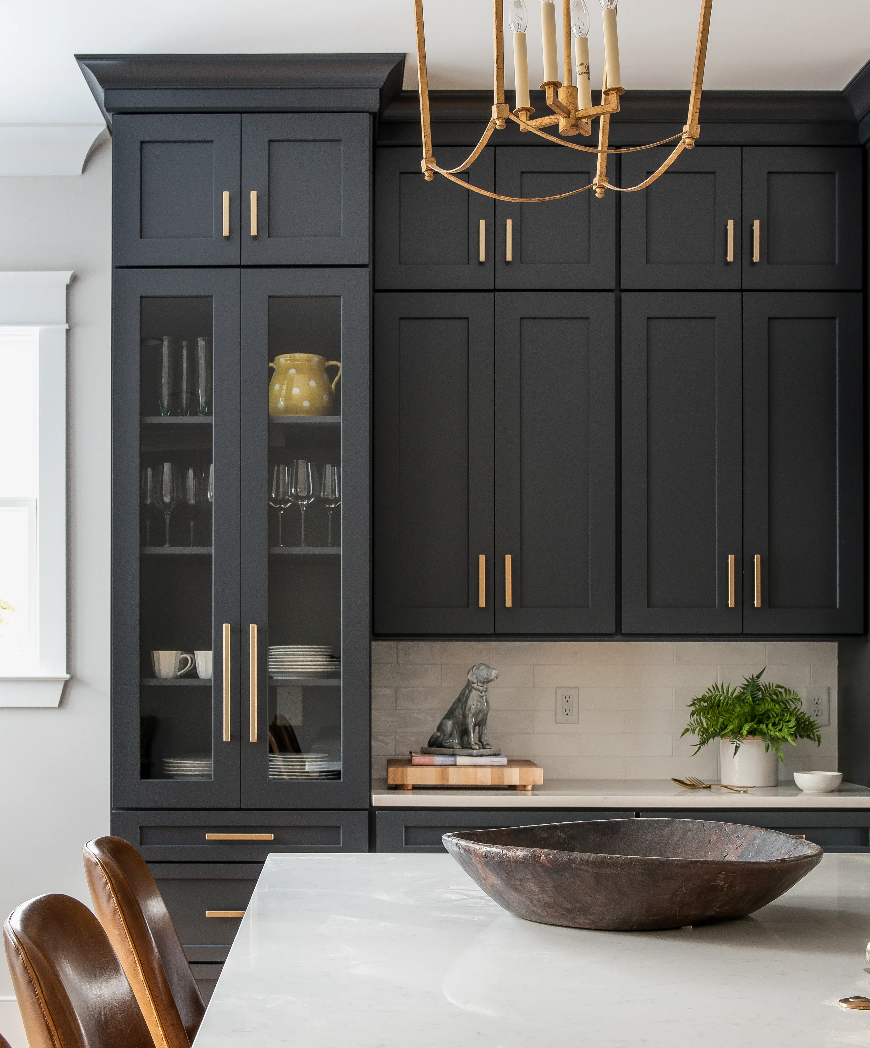 Charcoal glass-front hutch with brass pulls and styled shelves