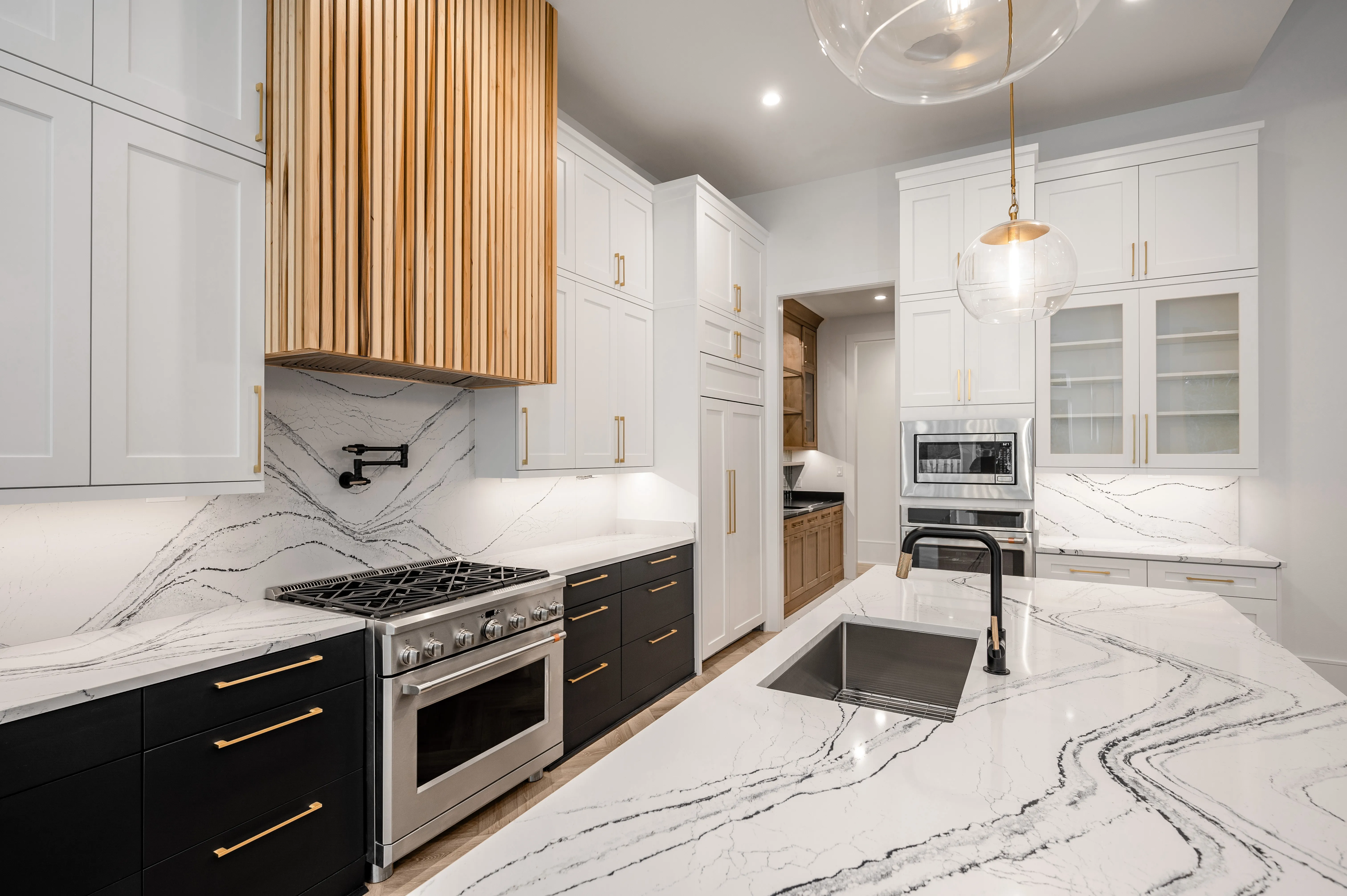 White Shaker uppers over black lowers with a slatted white-oak hood and veined quartz