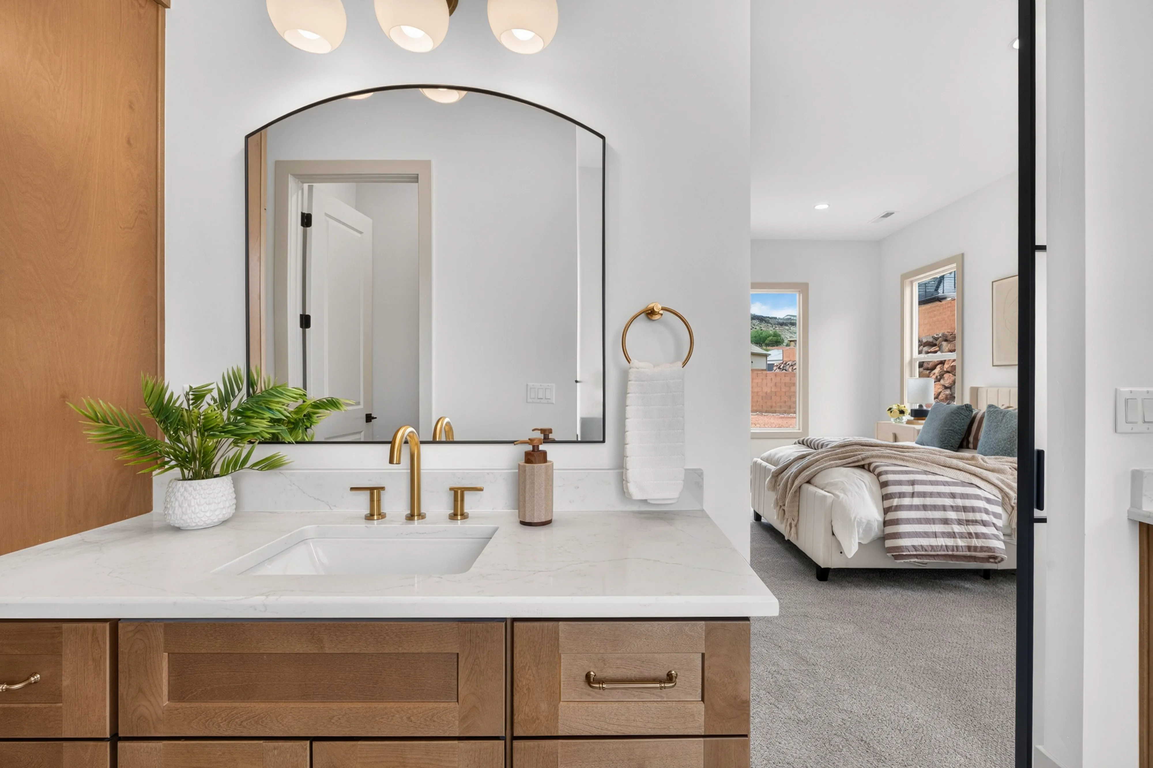 Oak vanity under an arched mirror with brass fixtures at 1927 Rimview Drive