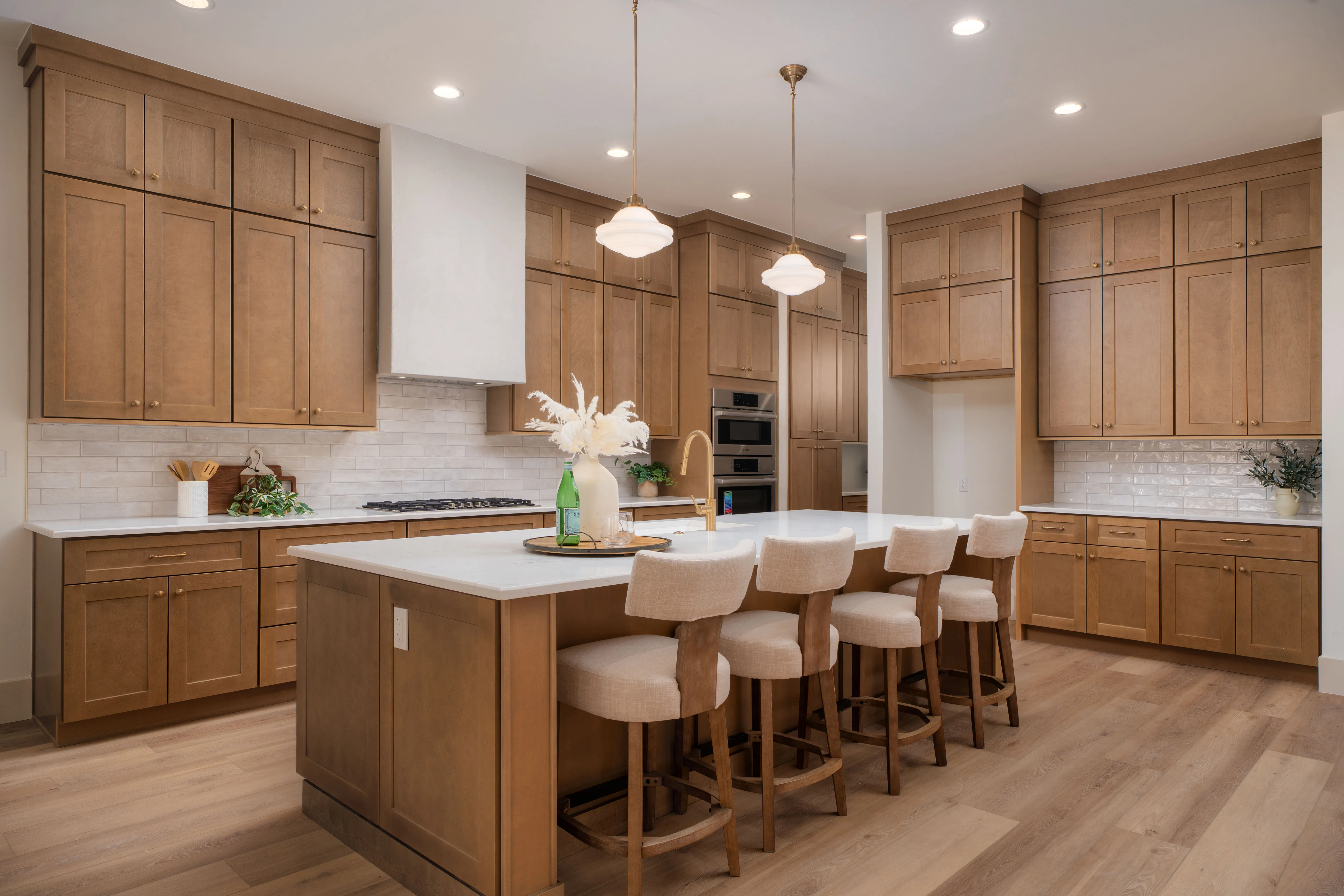 Honey-oak Lux Shaker kitchen from our Rimview project — double wall ovens, white quartz island with seating